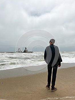 Sunken trawler, shipwreck. Ship Zeila at Skeleton Coast Namibia. Man stands.