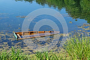 Sunken wooden boat on the river or lake near the shore.