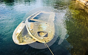 Sunken wooden boat in sea or lake tied to shore.