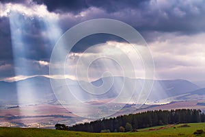 Sunlight beams over clouds in mountains. Rays in cloudy sky