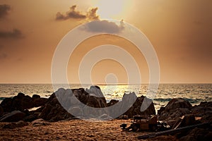 sunlight from behind clouds with rocks boat on foreground