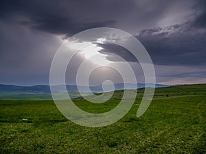 Sunlight breaking through the stormclouds over beautiful green meadow