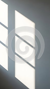 Sunlight casting geometric window shadows on a smooth gray wall