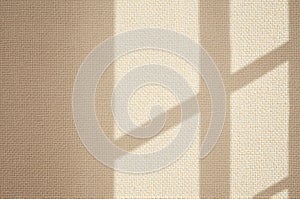 Sunlight casting window shadows on textured beige wall