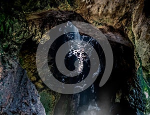 Sunlight coming through the opening roof of cave. Sun shining down in darkness photo