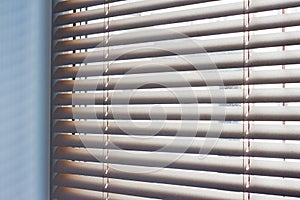 Sunlight coming through venetian blinds by the window .