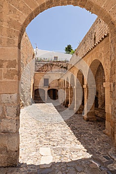 Sunlight dapples the cobbled courtyard of Almudaina Castle in Eivissa, inviting entry
