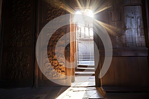 sunlight filtering through an elaborately carved wooden church door photo