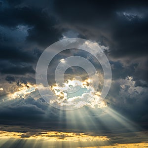 Sunlight filters through dense, dark clouds, creating dramatic rays known as