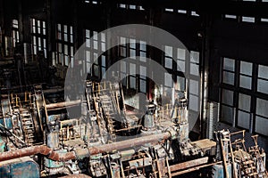 Sunlight illuminating old steel forming machinery inside a windowed warehouse