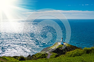 Sunlight over Cape Reinga Lighthouse and a winding path leading to it. Famous tourist attraction at Cape Reinga, Far