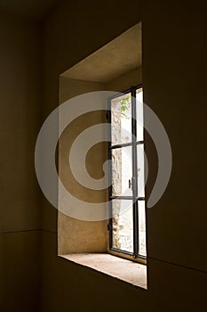 Sunlight passing through a vintage window in an old rural building with terra cotta walls