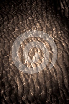 Sunlight reflecting on water ripples sand texture