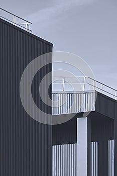 Sunlight and shadow on surface of corrugated metal industrial building against sky background in monochrome style