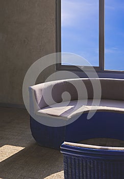 Sunlight and shadow on surface of curved couch near glass window on loft concrete wall in vintage living room