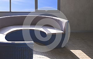 Sunlight and shadow on surface of empty curved couch near glass window on loft concrete wall in vintage living room