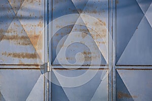 Sunlight on surface of polygon pattern of the old rusty steel folding gate door