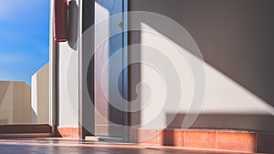 Sunlight and shadows on the fire extinguisher and wooden door surface in front of room inside of apartment