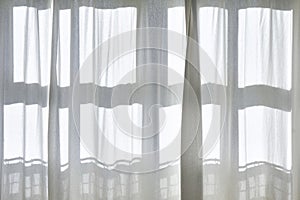 Sunlight shines through white transparent curtains