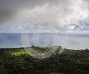 Sunlight shining through clouds onto a lush oceanside community with the ocean in the background in Palos Verdes, California