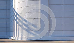 Sunlight and steel gate door shadow on curve surface of white prefabricated concrete block fence wall in front of building