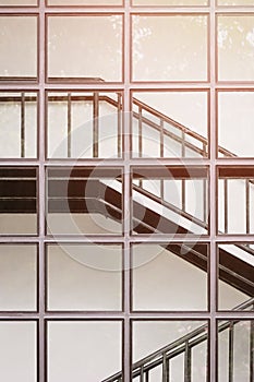 Sunlight on surface of glass wall with black metal staircase inside of modern building