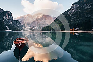 Sunlight is on the top. Wooden boat on the crystal lake with majestic mountain behind. Reflection in the water. Chapel