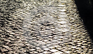 Sunlight on wet cobblestone road in the morning