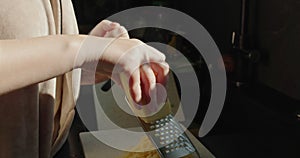Sunlight from the window shines on the hands of a woman as she grates cheese on a grater