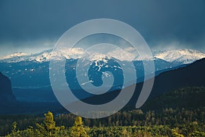 Sunlit alpine mountain range with snow tops during stormy weather in Inntal, Tirol, Austria