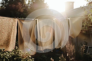 sunlit bedsheets hanging from line in town garden