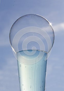 Sunlit bubble on glass of blue liquid