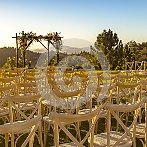 Sunlit chairs facing a Chuppah and a scenic view