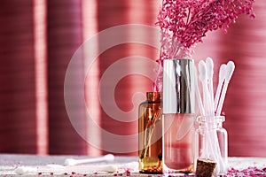 Sunlit cosmetic bottles with lip gloss, cotton buds on the makeup desk