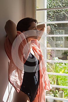 Sunlit freckled woman, wearing underwear and a pink pashmina scarf, holding her nape