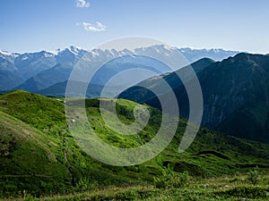 Sunlit green mountainsides surrounded by cliffs