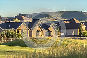 Sunlit hazards and fairway of a golf course with houses and hill background