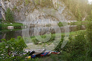 sunlit landscape with catamarans on the shore of mountain river, around the forest and green grass