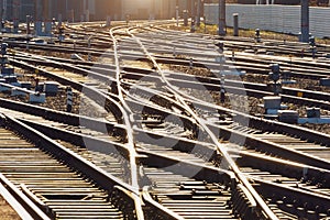 Sunlit railway road, rails and crossing of railway arrows reflect bright light
