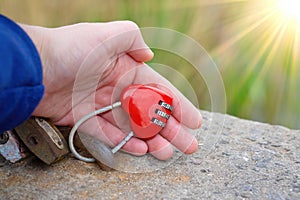 Sunlit red heart shaped combination lock in hand