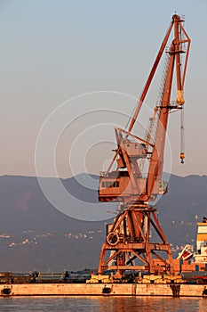 Sunlit red port crane in empty morning harbor of Rijeka Croatia