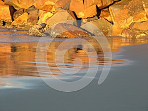 Sunlit rocks on sandy beach