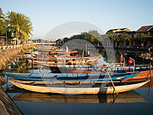 Sunlit Row of Wooden Fishing Boats in the Thu Bon River in Hoi An