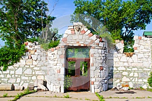 Sunlit Ruins of a Stone Structure with Locked Gate in Lush Greenery