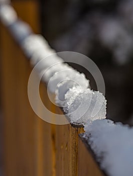 Sunlit snow on top of cedar fence in backyard