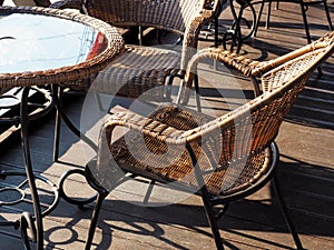 Sunlit wicker chairs sit at the table on a wooden veranda. Street Cafe