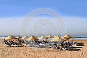 Sunlounger and sunshades in a row on the beach