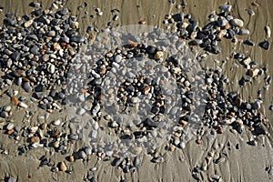 Sunny autumn day on the Aegean Sea. Texture of wet pebbles on beach sand.
