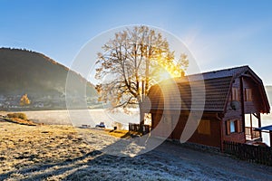 Sunny autumn landscape, wooden house at the alpine lake