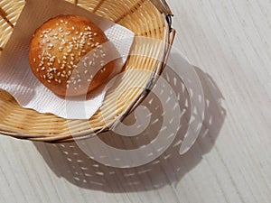 Sunny Breadbasket with long shadow on white wooden table top view. Closeup Bun in basket modern banner snack food